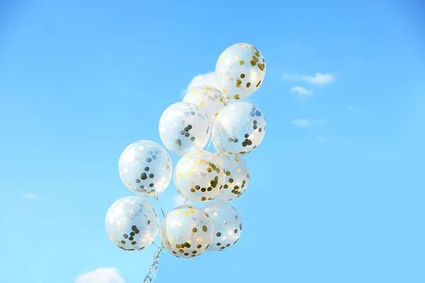 Glitter balloons against blue sky on sunny day outdoors