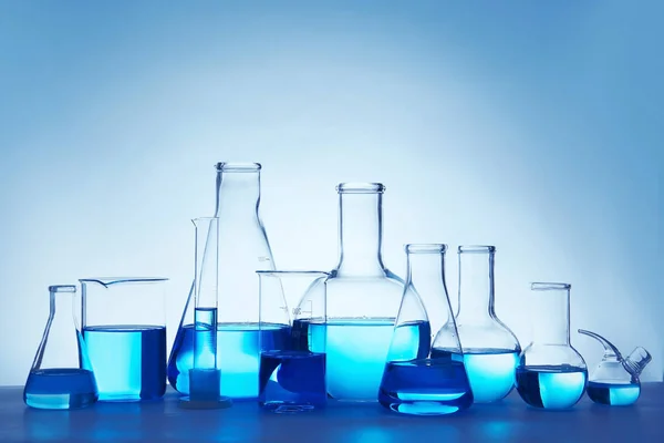 Vidros Laboratório Para Análise Química Com Líquido Azul Mesa Contra — Fotografia de Stock