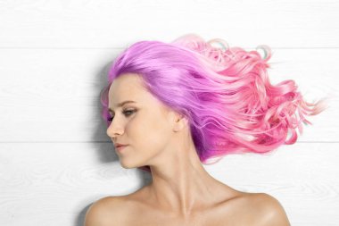 Beyaz ahşap arka planda, üstten görünüm boyalı uzun kıvırcık saçlı Genç kadın portresi. Son moda saç tasarım 