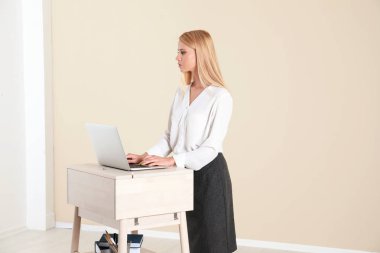 İşyerinde ışık duvara ayağa, dizüstü bilgisayar kullanan genç kadın