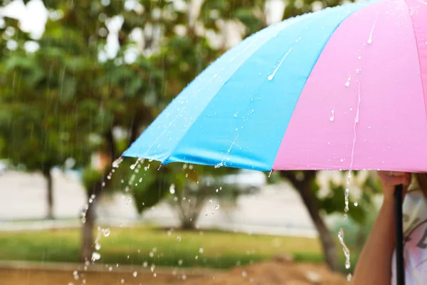 Person with bright umbrella under rain on street, closeup