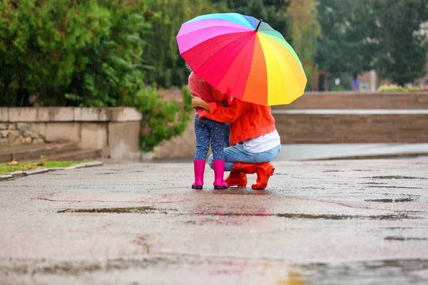 母と娘は屋外の雨の下で明るい傘 — ストック写真