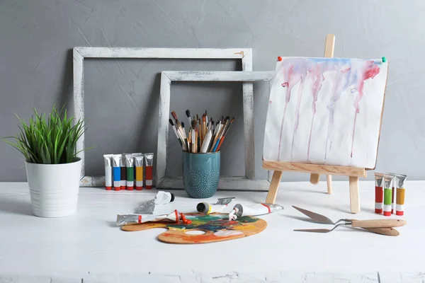 画架与抽象绘画和一套专业艺术供应在桌反对灰色背景 — 图库照片