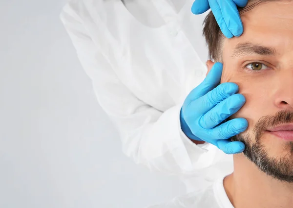 Dokter Memeriksa Wajah Pria Dewasa Sebelum Operasi Kosmetik Pada Latar — Stok Foto