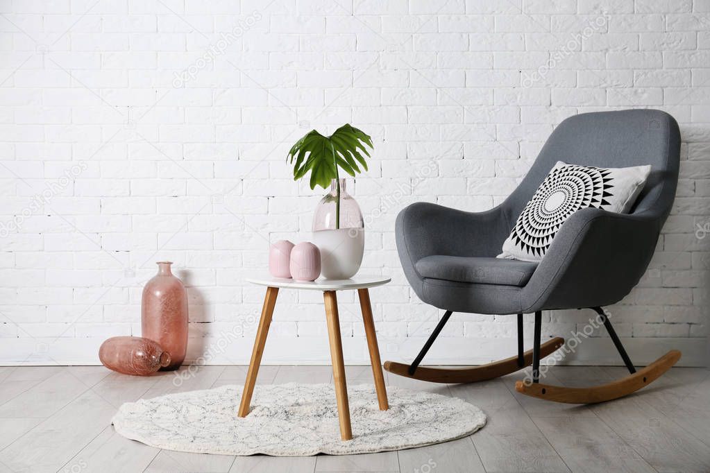 Living room interior with vases on coffee table and comfortable armchair near white wall