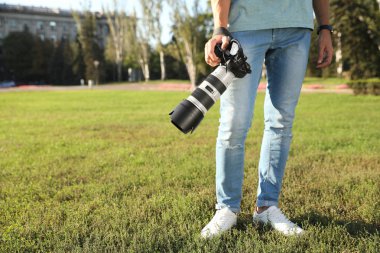 Genç erkek fotoğrafçı profesyonel kamera açık havada tutarak. Metin için yer