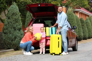 Mutlu genç aile araba bagajı yakınındaki açık havada bavul ile yüklü