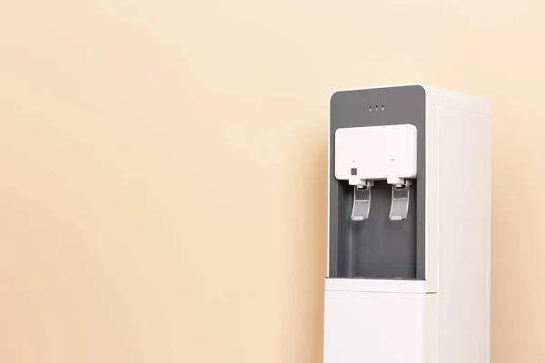 Modern water cooler against color background with space for text