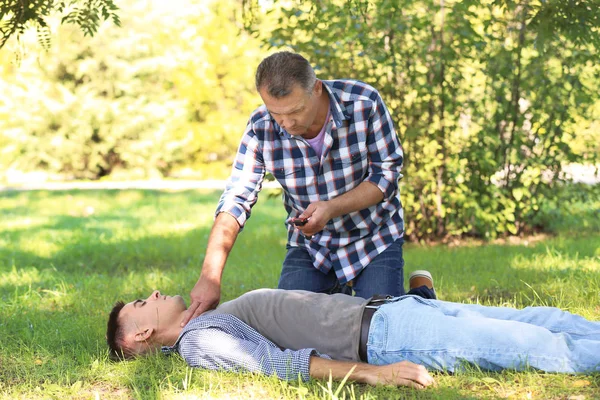 Baygın adam açık havada yardım geçenler. İlk yardım