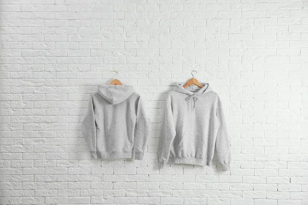 Nieuwe Hoodie Sweaters Met Hangers Bakstenen Muur Mockup Voor Ontwerp — Stockfoto