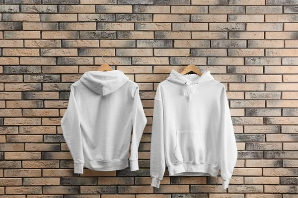 Nieuwe Hoodie Sweaters Met Hangers Bakstenen Muur Mockup Voor Ontwerp — Stockfoto
