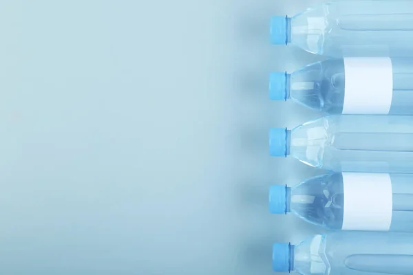 Bottles of water on light background, top view. Space for text