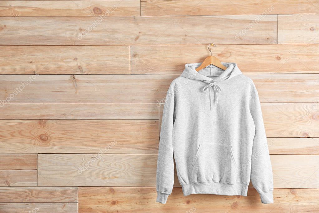 New hoodie sweater with hanger on wooden wall. Mockup for design