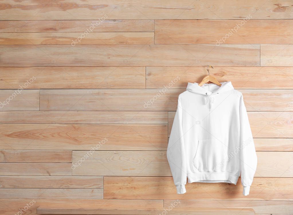 New hoodie sweater with hanger on wooden wall. Mockup for design