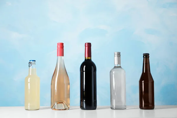 Flaskor Med Olika Alkoholhaltiga Drycker Bordet Mot Färg Bakgrunden — Stockfoto