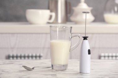 Süt frother aygıt, cam bardak ve kaşık mutfak masasında