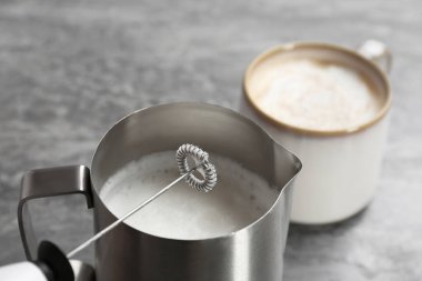 Milk frother with pitcher on table, closeup clipart