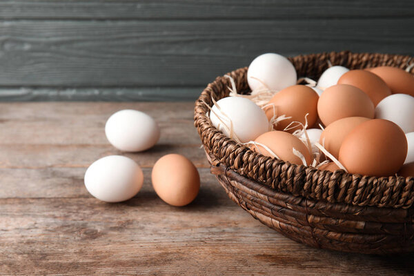 Basket with raw chicken eggs on wooden table