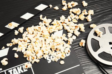 Lezzetli patlamış mısır, film makaraları ve Klaket ahşap masa üzerinde. Sinema snack