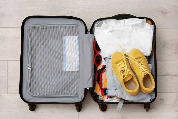 Gepackter Koffer Mit Kleidung Und Turnschuhen Auf Holzgrund Draufsicht — Stockfoto