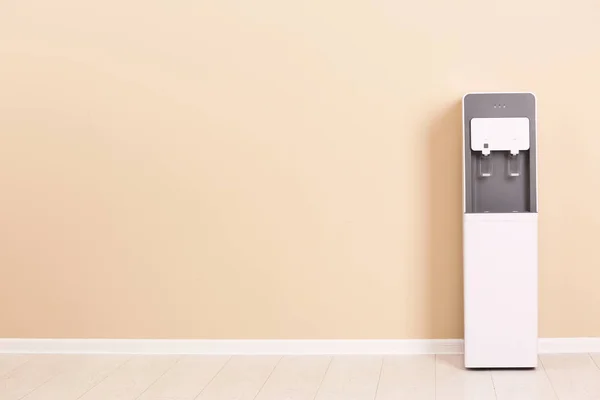 Modern water cooler against color wall with space for text