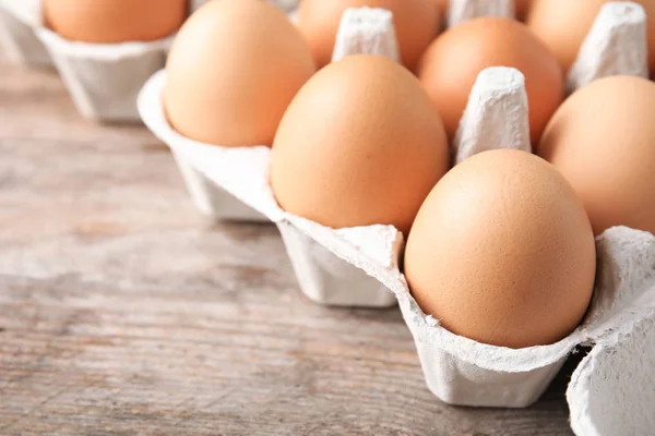 Carton of eggs on wooden table, closeup view