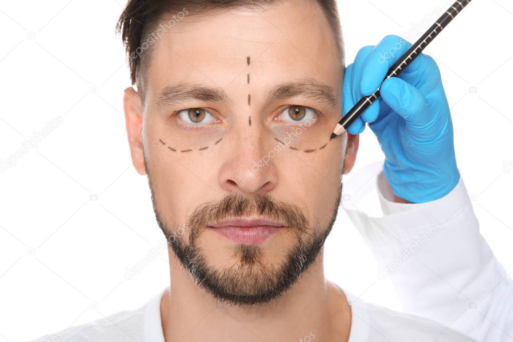 Doctor marking mature man face before cosmetic surgery on white background