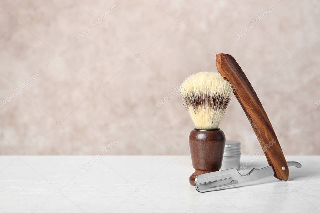 Shaving accessories on table against color background with space for text