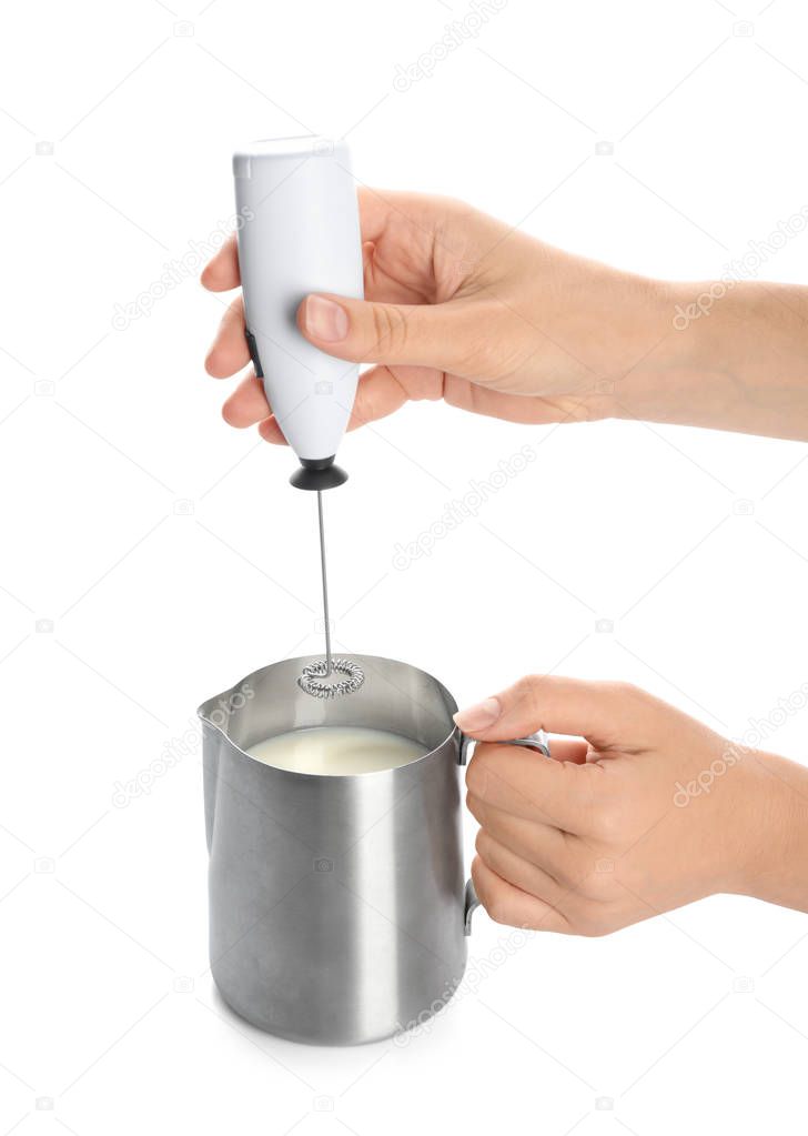 Woman using milk frother device in pitcher on white background