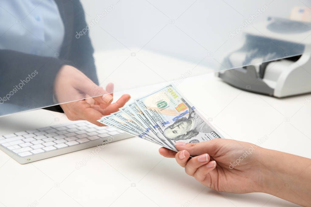 Woman giving money to teller at cash department window, closeup