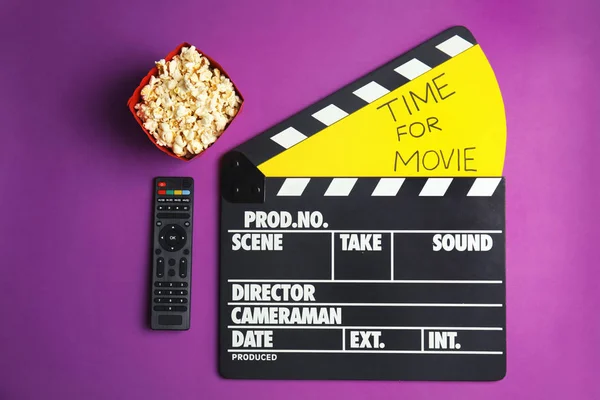 Flat lay composition with popcorn, cinema clapperboard and TV remote on color background