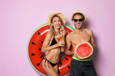 Mutlu genç çift beachwear şişme yüzüklü ve renk arka plan üzerinde kokteyl