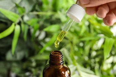 Pipet ile petrol şişe üzerinde tutan kadın arka plan bulanık