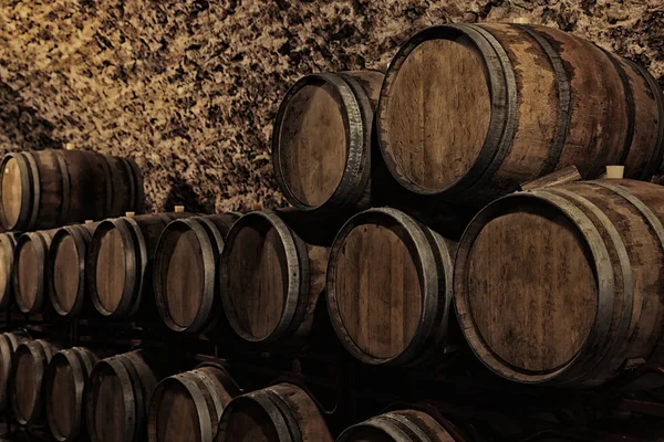 Wooden barrels with whiskey near stone wall in dark cellar