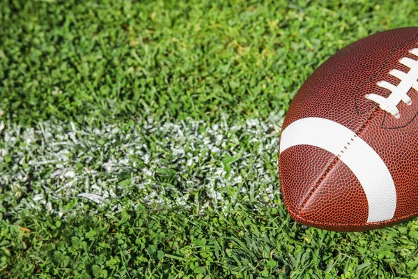 新鮮な緑の野原の草のアメリカン フットボールのボール テキストのためのスペース — ストック写真