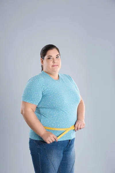 太りすぎの女性の色の背景上の重量損失の前に腰を測定 — ストック写真