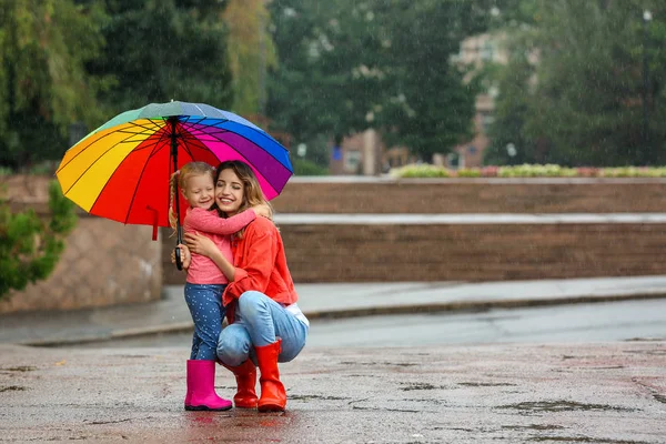 幸せな母と娘は屋外の雨の下で明るい傘 — ストック写真