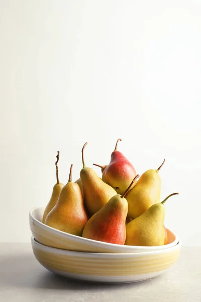 Plate with ripe pears on table against light background. Space for text