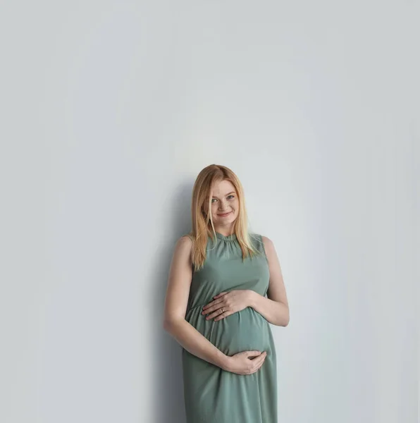 Jonge Zwangere Vrouw Aanraken Van Buik Lichte Achtergrond — Stockfoto