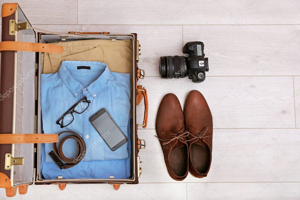 Packed suitcase on wooden background, top view. Space for text