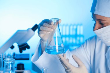 Laboratuarda test şişesi örnek ile tutan kadın bilim adamı. Kimyasal analiz