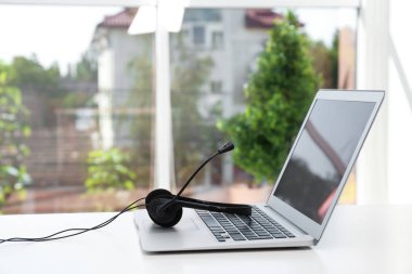 Modern laptop ve kulaklık masada kapalı. Teknik destek kavramı
