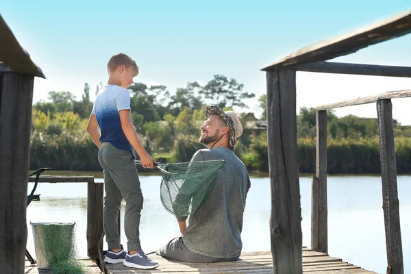 Father and son fishing together on sunny day