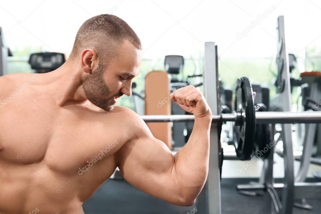 Shirtless strong young man posing in gym