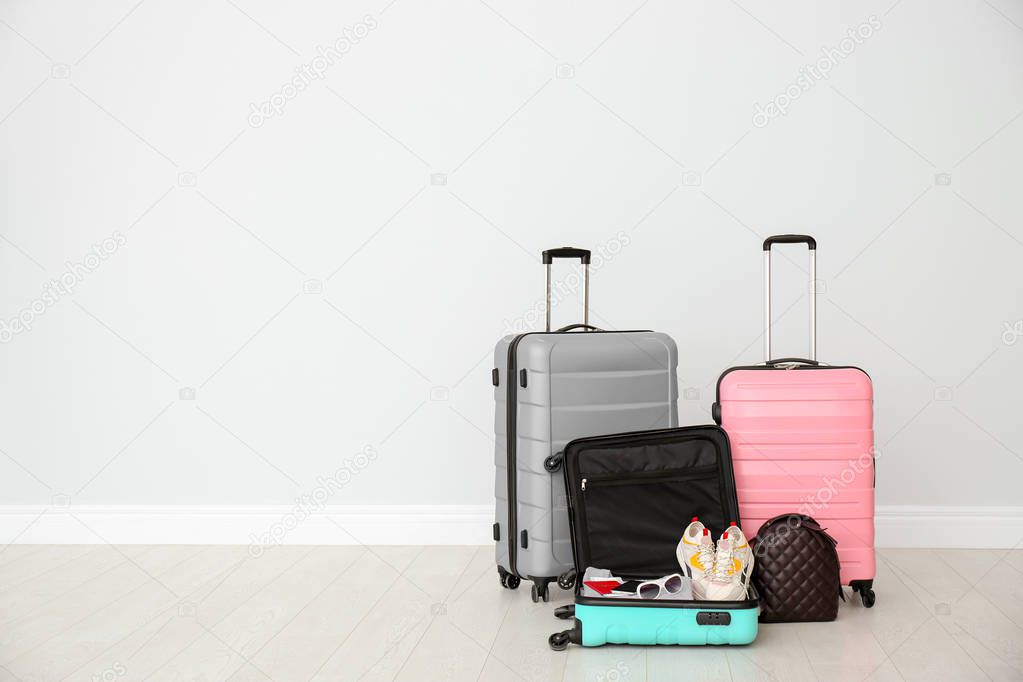 Modern suitcases on floor near light wall. Space for text