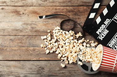 Lezzetli patlamış mısır, film makaraları ve Klaket ahşap arka plan, metin için yer ile üstten görünüm üzerinde. Sinema snack