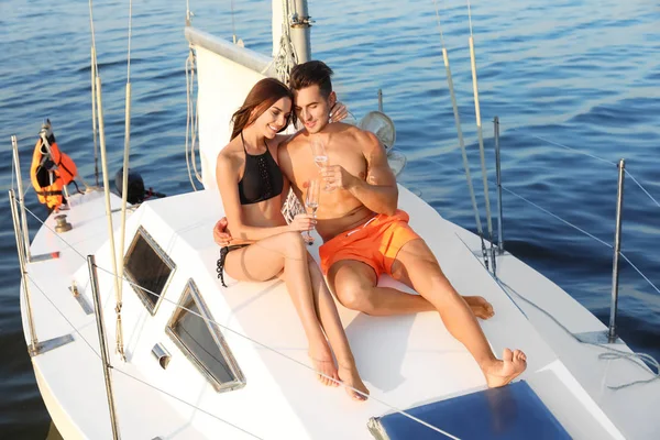若い男と彼のガール フレンドをヨットの上でシャンパンを飲んでビキニで — ストック写真