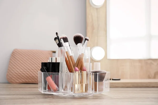 Organizer with cosmetic products for makeup on table near mirror