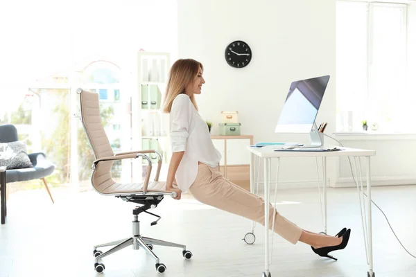 Young beautiful businesswoman stretching in office. Workplace fitness