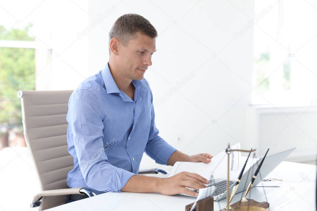 Male notary working with laptop at table in office, closeup